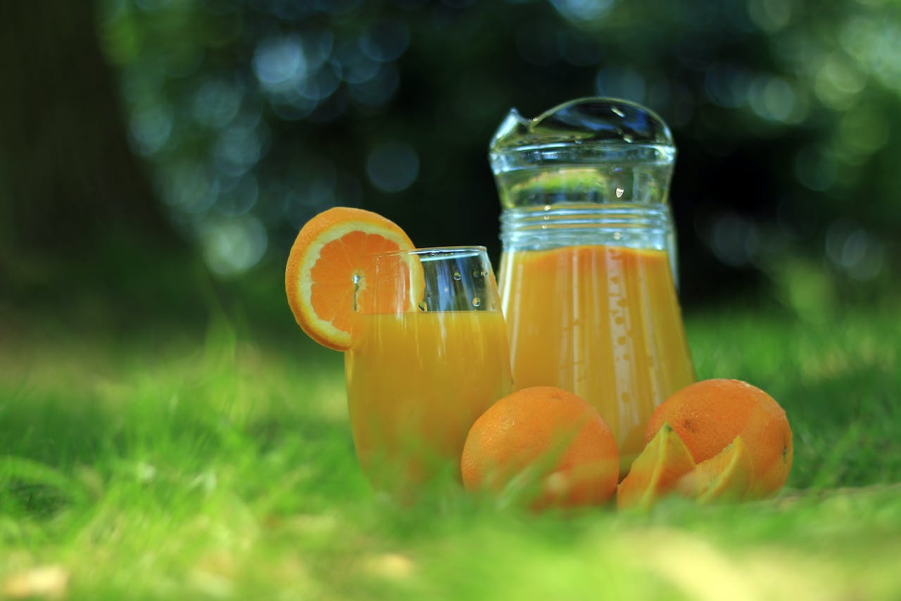 Una jarra y un vaso con zumo de naranja